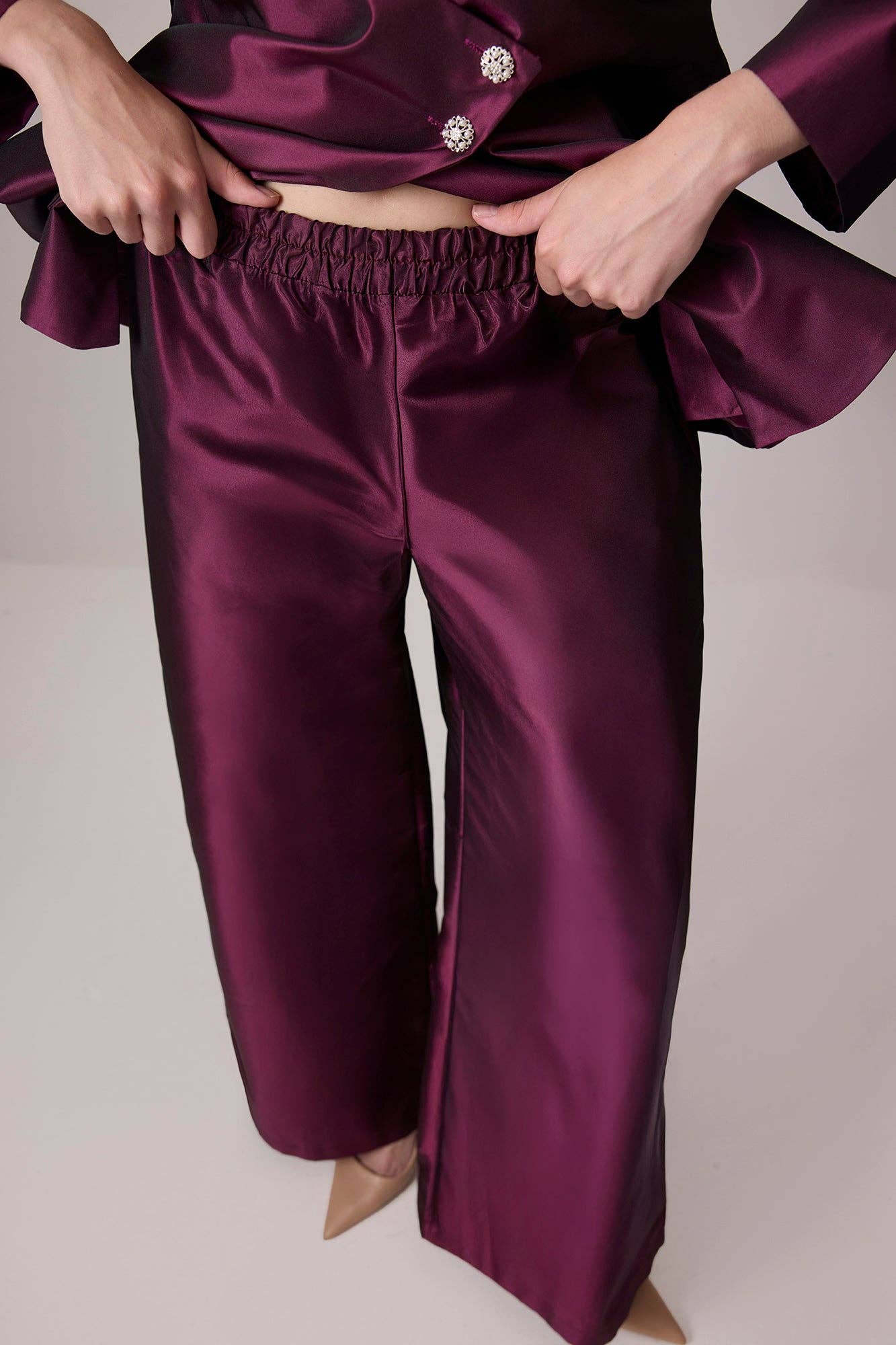 Completo in raso bordeaux con giacca asimmetrica e pantaloni a gamba larga