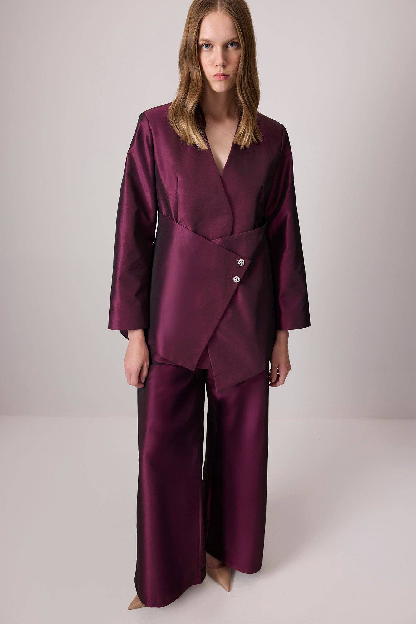 Completo in raso bordeaux con giacca asimmetrica e pantaloni a gamba larga