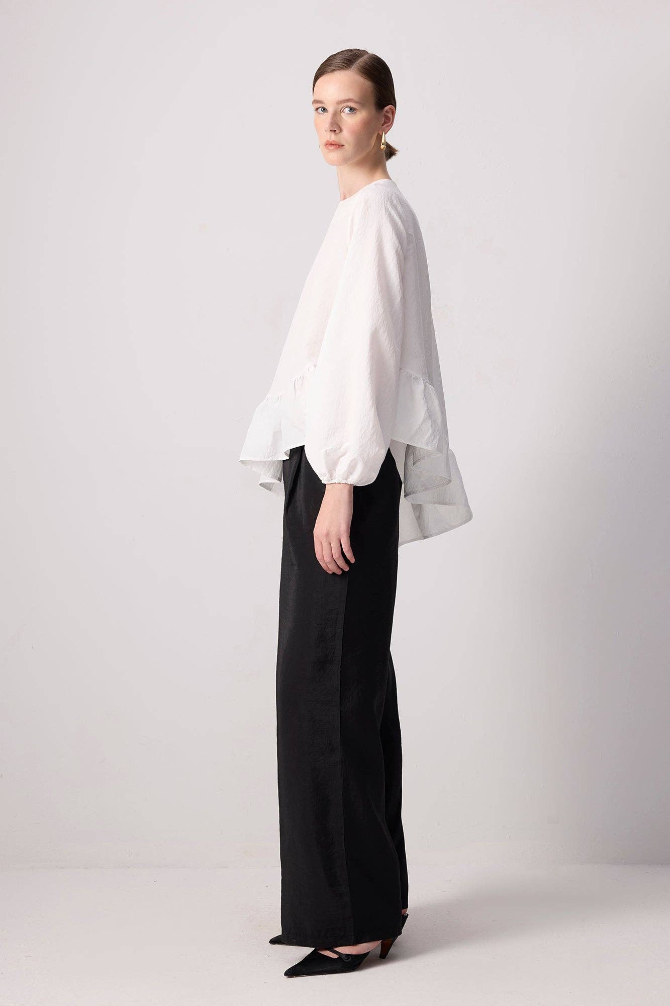Blusa bianca con balza asimmetrica e maniche a palloncino