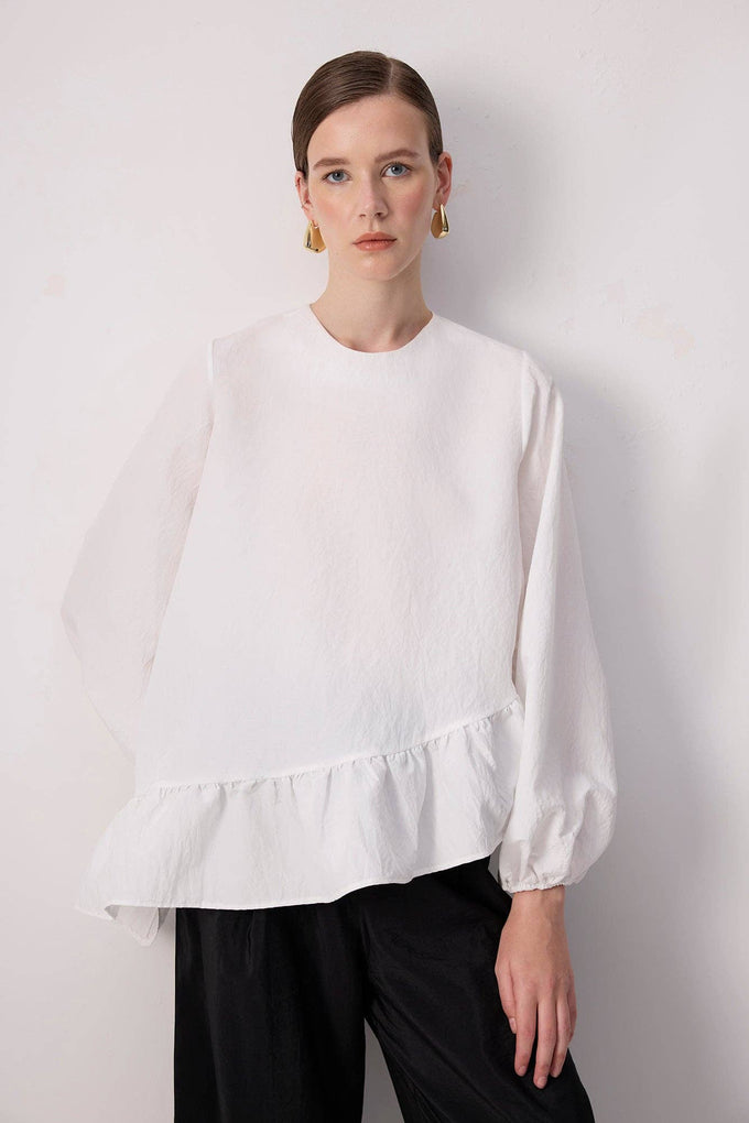 Blusa bianca con balza asimmetrica e maniche a palloncino