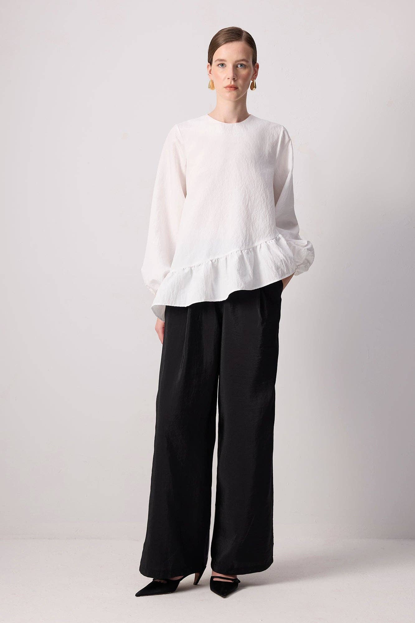 Blusa bianca con balza asimmetrica e maniche a palloncino