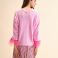 Maglia rosa con polsini in piume