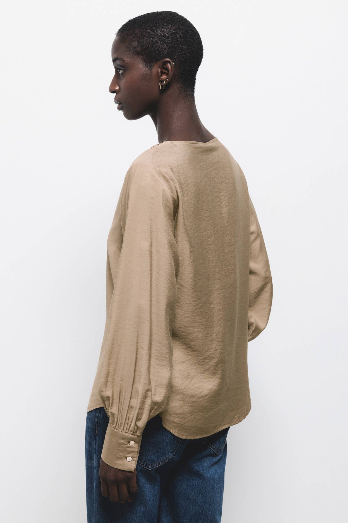 Blusa beige con scollo a V e dettagli di paillettes