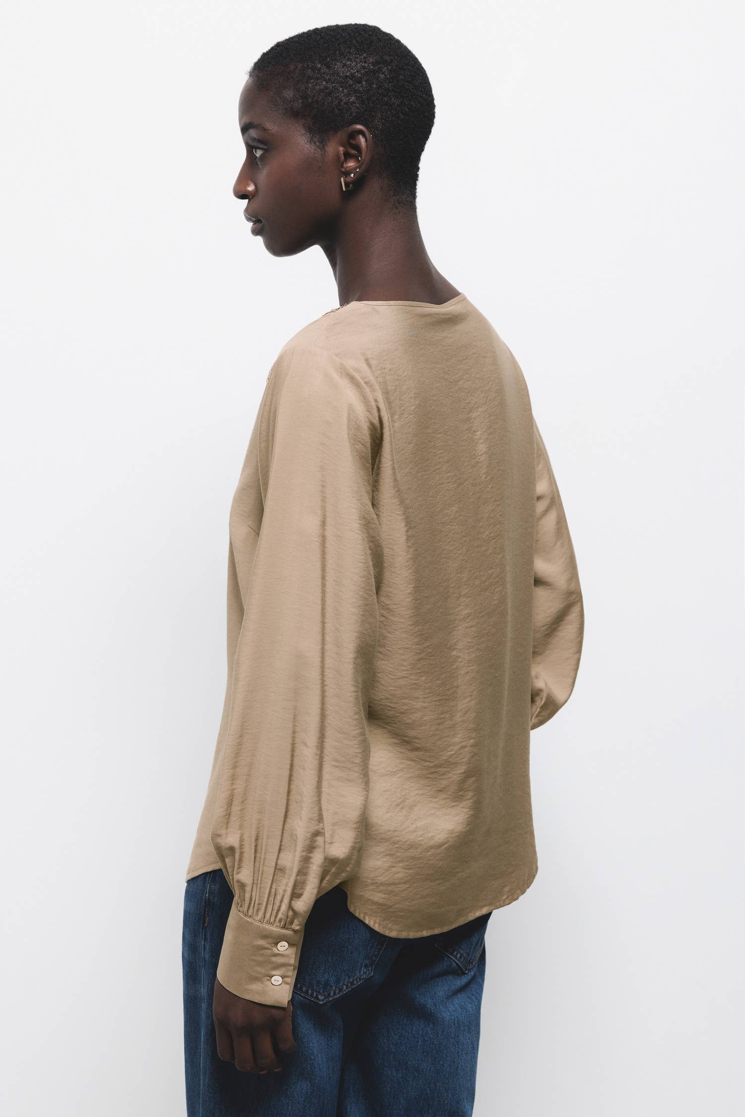 Blusa beige con scollo a V e dettagli di paillettes