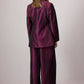 Completo in raso bordeaux con giacca asimmetrica e pantaloni a gamba larga