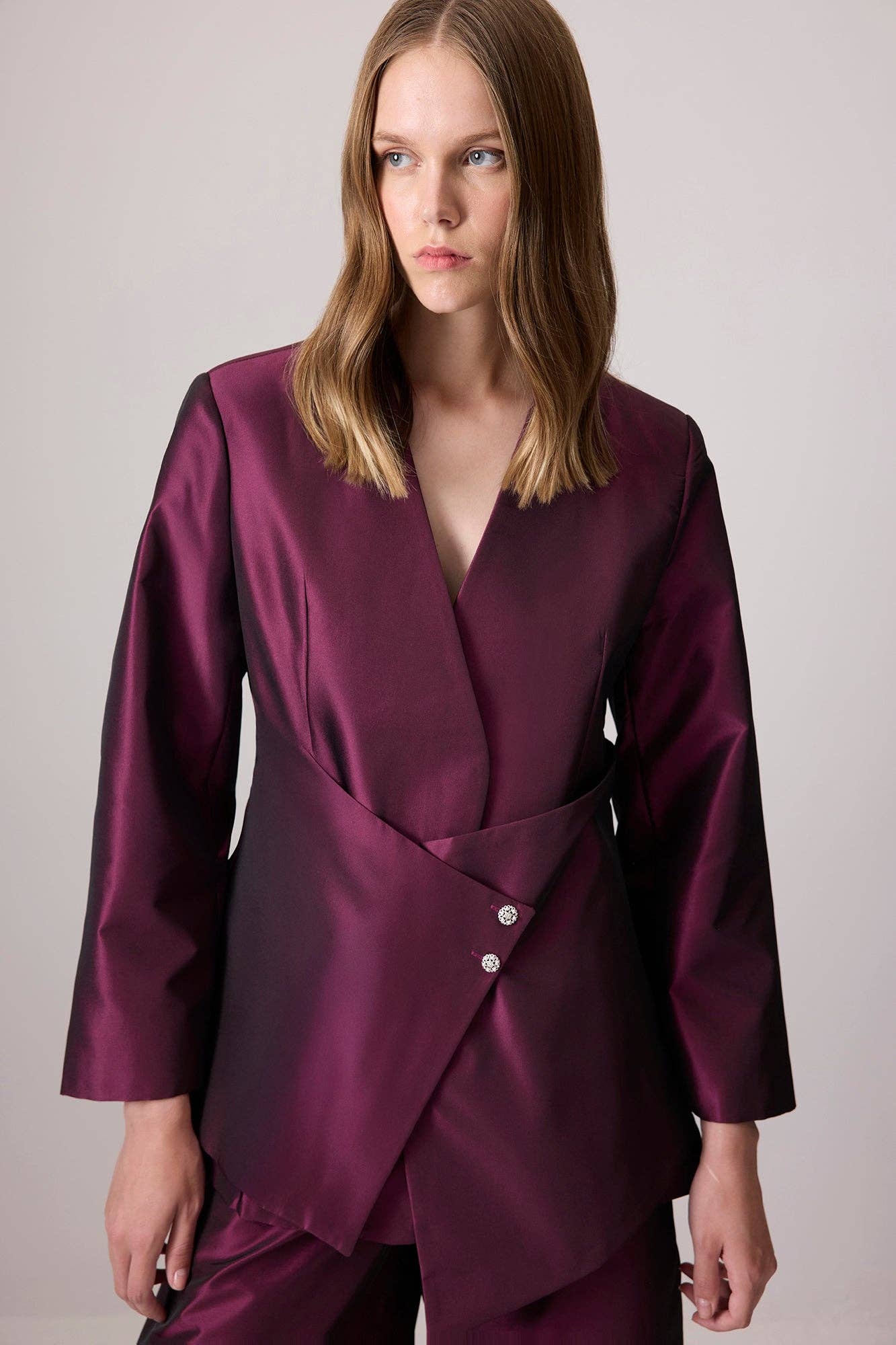 Completo in raso bordeaux con giacca asimmetrica e pantaloni a gamba larga