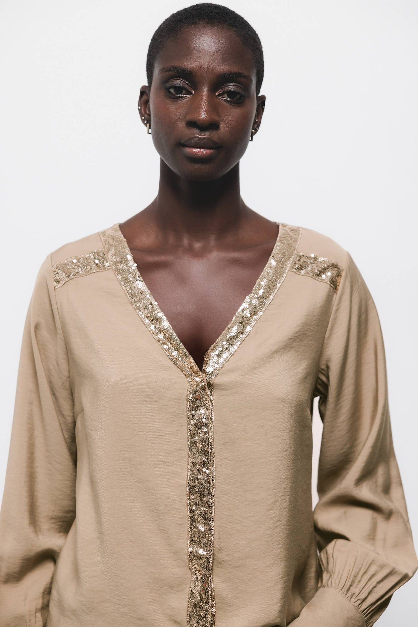 Blusa beige con scollo a V e dettagli di paillettes