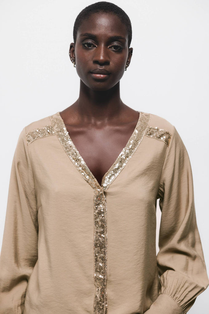 Blusa beige con scollo a V e dettagli di paillettes