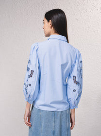 Blusa azzurra con maniche ricamate