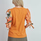 Top in cotone arancione con maniche a sbuffo floreali