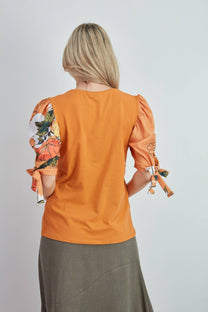 Top in cotone arancione con maniche a sbuffo floreali