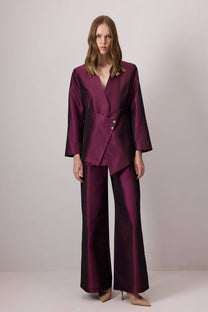 Completo in raso bordeaux con giacca asimmetrica e pantaloni a gamba larga