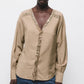 Blusa beige con scollo a V e dettagli di paillettes